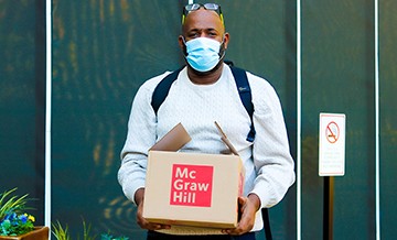 A man carrying a box of food from a community food distribution