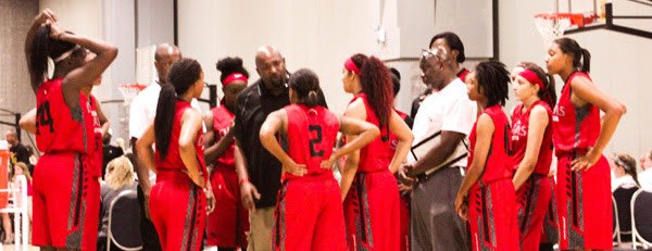 Coaches huddled with a girls basketball team during a game